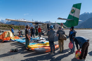 A group of kayakers with all of their gear laid out getting ready to get on an airplane in Nepal