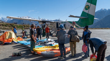 A group of kayakers with all of their gear laid out getting ready to get on an airplane in Nepal