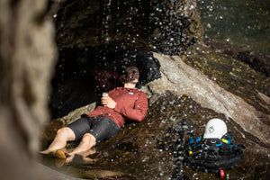 A man laying on a rock in Immersion Research top and shorts.