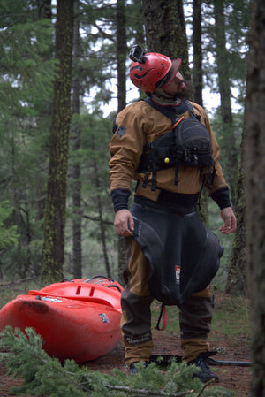 Person in forest gear with a red kayak, surrounded by trees