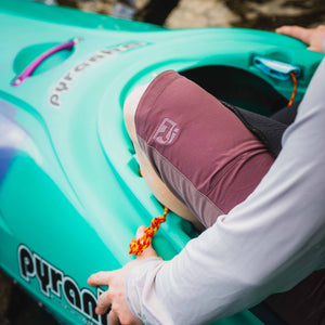 Person sitting in a teal kayak with a blurred natural background