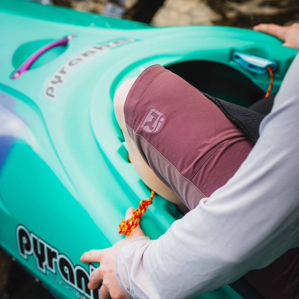 Person sitting in a teal kayak with a blurred natural background