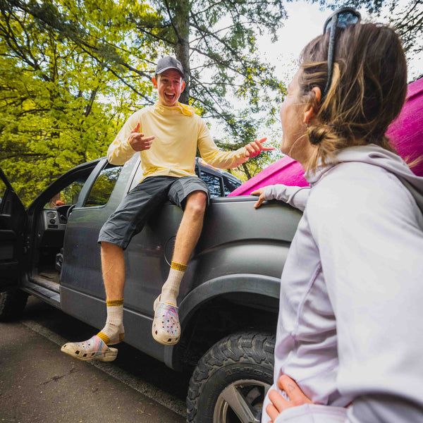 Two people interacting with a car in a forested area
