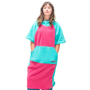 Person wearing a pink and teal poncho with a visible brand logo on a white background