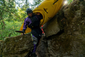 Kayaker hiking with his boat in Immersion Research gear.
