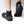 A person wearing black neoprene boot covers with black rubber soles, shown from the calves down on a clean white studio background. A white IR logo.