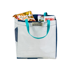 Recycled Billboard Grocery bag filled with packs of instant ramen noodles.