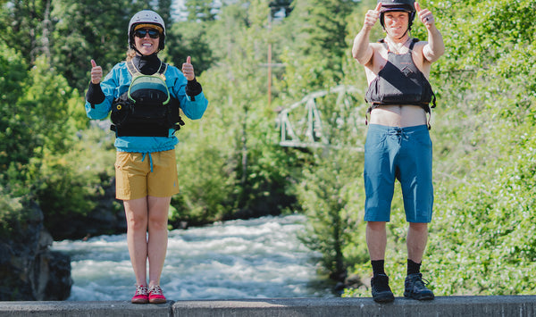 Anna Wagner and Sam Swanson giving two thumbs up standing on the bridge above the river.