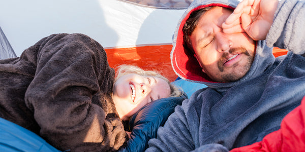 A woman and man laying in a tent wearing hot lap hoodies by Immersion Research.