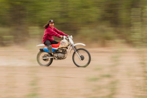 A girl riding a dirt bike and wearing a hot lap hoodie by Immersion Research.