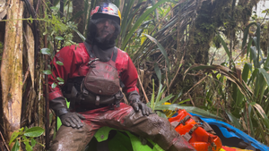 Expedition kayaker, Nouria Newman, covered in mud sitting in the jungle wearing an Immerison Research Dry Suit.