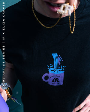 A person biting a gold chain wearing a graphic tshirt designed by eliza carver.