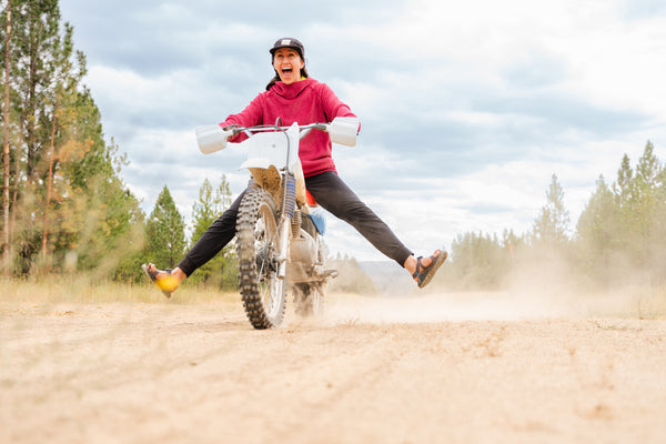 A girl riding a dirt bike and wearing a hot lap hoodie by immersion research.